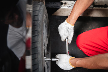 A man is working on a car tire, using a wrench to loosen it