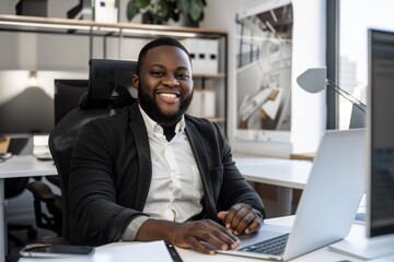 A cheerful African American businessman works at his computer in a well-organized office space, portraying confidence