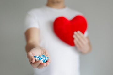 Man holding red heart pillow and pills in hands with copyspace