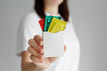 Woman in white tshirt showing package of colorful condoms with copyspace