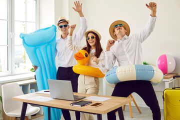 Funny happy business people standing in office on their workplace with beach air mattress holding...