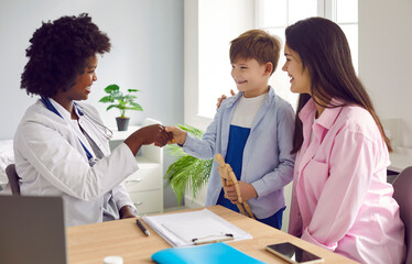 Smiling friendly woman african american pediatrician doctor shaking hands with a little child boy...