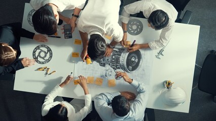 Top down aerial view of smart engineer team working together to design turbine engine. Professional...