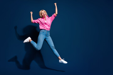 Fototapeta premium Full size photo of pretty young girl jump celebrate champion raise fists wear trendy pink outfit isolated on dark blue color background