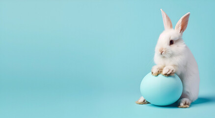Naklejka na ściany i meble A cute white rabbit sitting on a blue Easter egg. The concept of Easter.