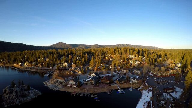 Aerial Tilt Up Shot Of Lake And Structures In Snow Covered Forest - Big Bear Lake, California