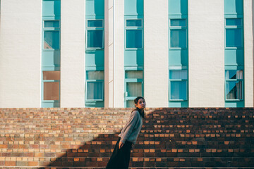 a woman standing on a modern building in the sunlight