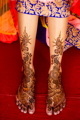 Bridal henna pattern tattoo on legs and feet in colorful saree