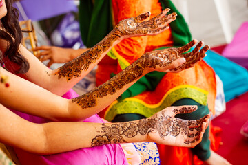 Women with henna tattoos on their arms and hands at mehendi ceremony