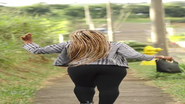 A woman with dreadlocks goes for a walk in different locations, showcasing urban and natural settings. The video captures her in motion, expressing a sense of freedom and exploration