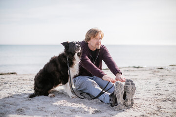 Mature man working out with his border collie dog on the beach