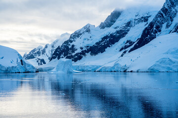 Expedition cruise ship passing through Lemaire channel in Antarctica at sunrise