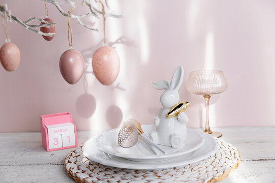 Table place setting with easter bunny figure, eggs and wooden Perpetual calendar