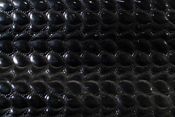 A close up of a black leather item with a pattern of small black dots