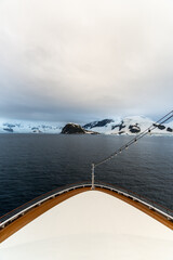 Expedition cruise ship passing through Lemaire channel in Antarctica at sunrise