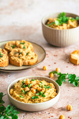 Hummus, chickpea puree in a bowl and on toasted bread slices