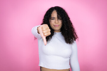 African american woman wearing casual sweater over pink background with angry face, negative sign...