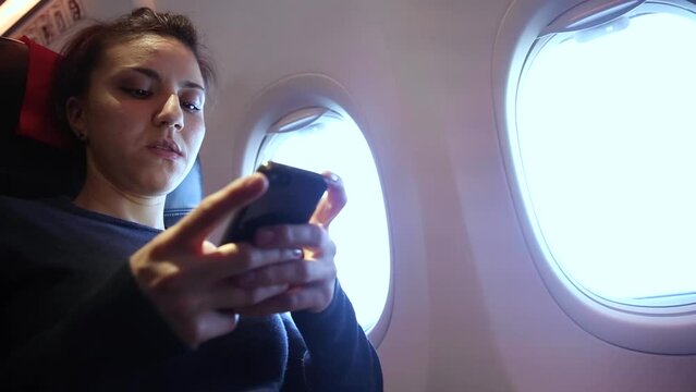 Woman on a plane using mobile phone during flight