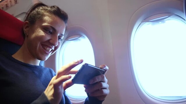 Woman on a plane using smartphone to take photos through the window