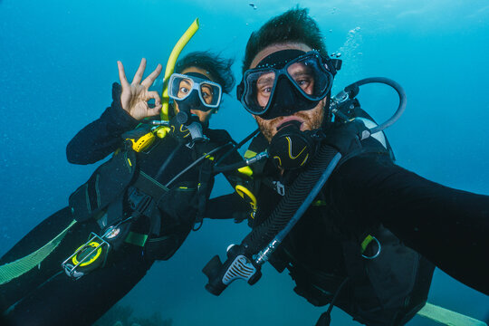 Two people are underwater, one of them is taking a selfie