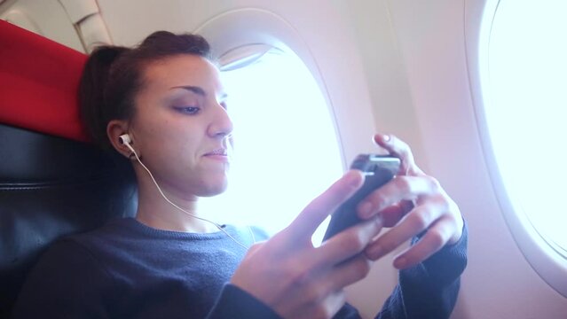 Woman on a plane listening to music with her smartphone