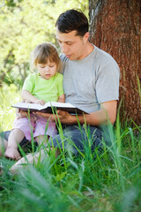 happy father with a child reading a book on the nature of the Bible