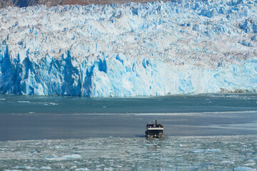 Sightseeing boat dwarfed by the ice wall of South Sawyer Glacier at the end of Tracy Arm Fjord in...