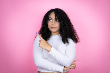 African american woman wearing casual sweater over pink background confused and pointing with hand...