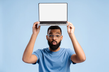 Excited, bearded African American man holding laptop with white blank screen looking at camera