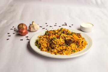 Mughlai Beef Biryani rice pulao with garlic, onion and raita served in plate isolated on background side view of indian and pakistani traditional food