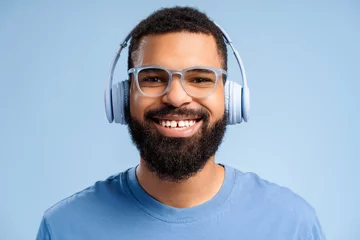 Photo sur Plexiglas Magasin de musique Handsome, smiling African American man wearing headphones and stylish eyeglasses, listening to music