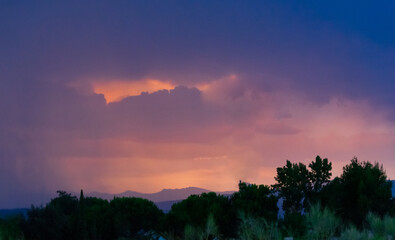Twilight sky with vivid orange and purple clouds over mountain silhouette