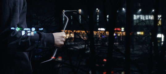 A burglar with a crowbar is preparing to break into a store. - obrazy, fototapety, plakaty