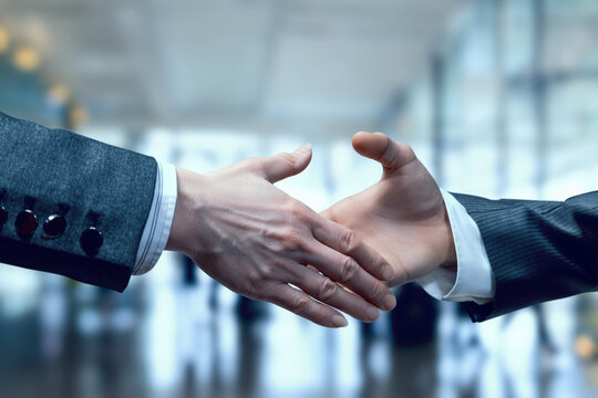 Businessmen reach out to shake hands.