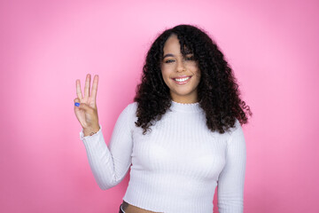 African american woman wearing casual sweater over pink background showing and pointing up with fingers number three while smiling confident and happy