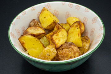 Bowl of crispy fried potatoes. Close-up with dark background