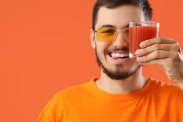 Young man with glass of juice on red background, closeup