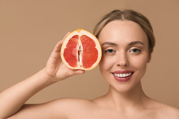 Young woman with grapefruit on beige background, closeup