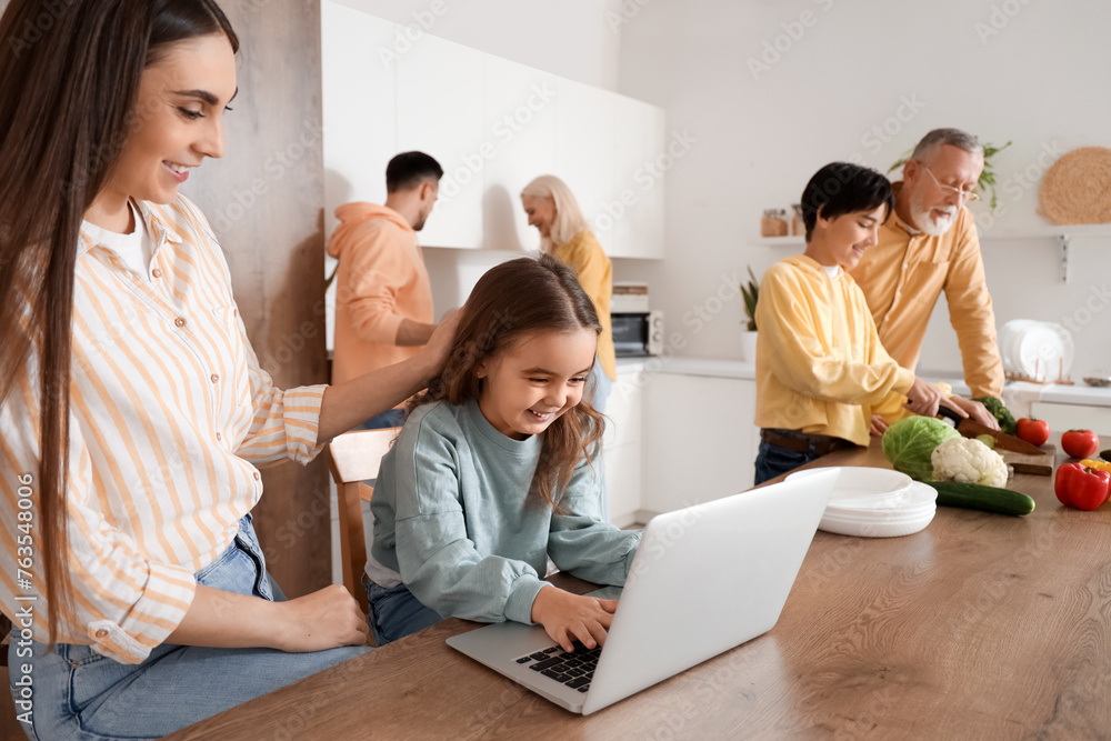 Poster Little girl using laptop and her family in kitchen