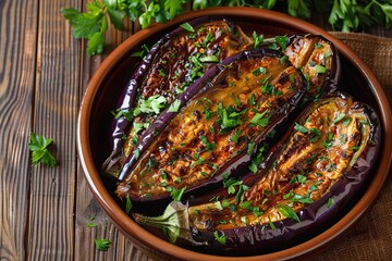 Baked eggplants in plate on wooden table