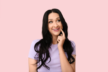 Fototapeta premium Beautiful young woman with dark wavy hair on pink background