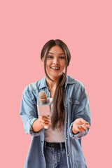 Female Asian journalist with microphone on pink background