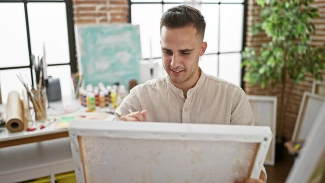 Hispanic man painting in a bright studio, exuding creativity, focus, and artistic skill.