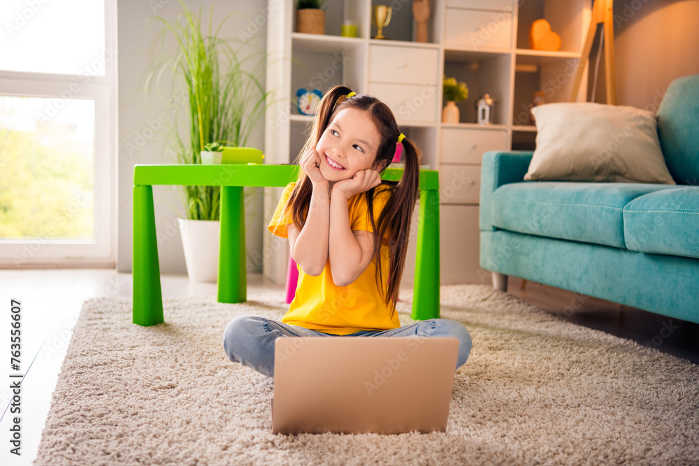 Poster photo portrait of cute small girl sit floor netbook look admire empty space dressed stylish yellow c