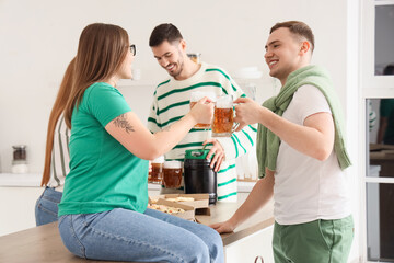 Young friends with beer celebrating St. Patrick's Day in kitchen