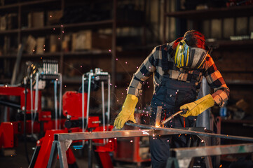 Craftsman welding the metal construction with great care and patience.
