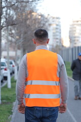 view of a man walking with orange safety vest