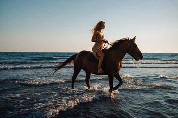 A young attractive woman is horseback riding at seaside.
