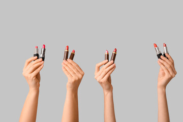 Female hands with different lipsticks on white background