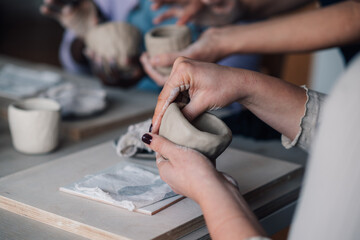 Close up of pottery class student making earthenware on workshop.